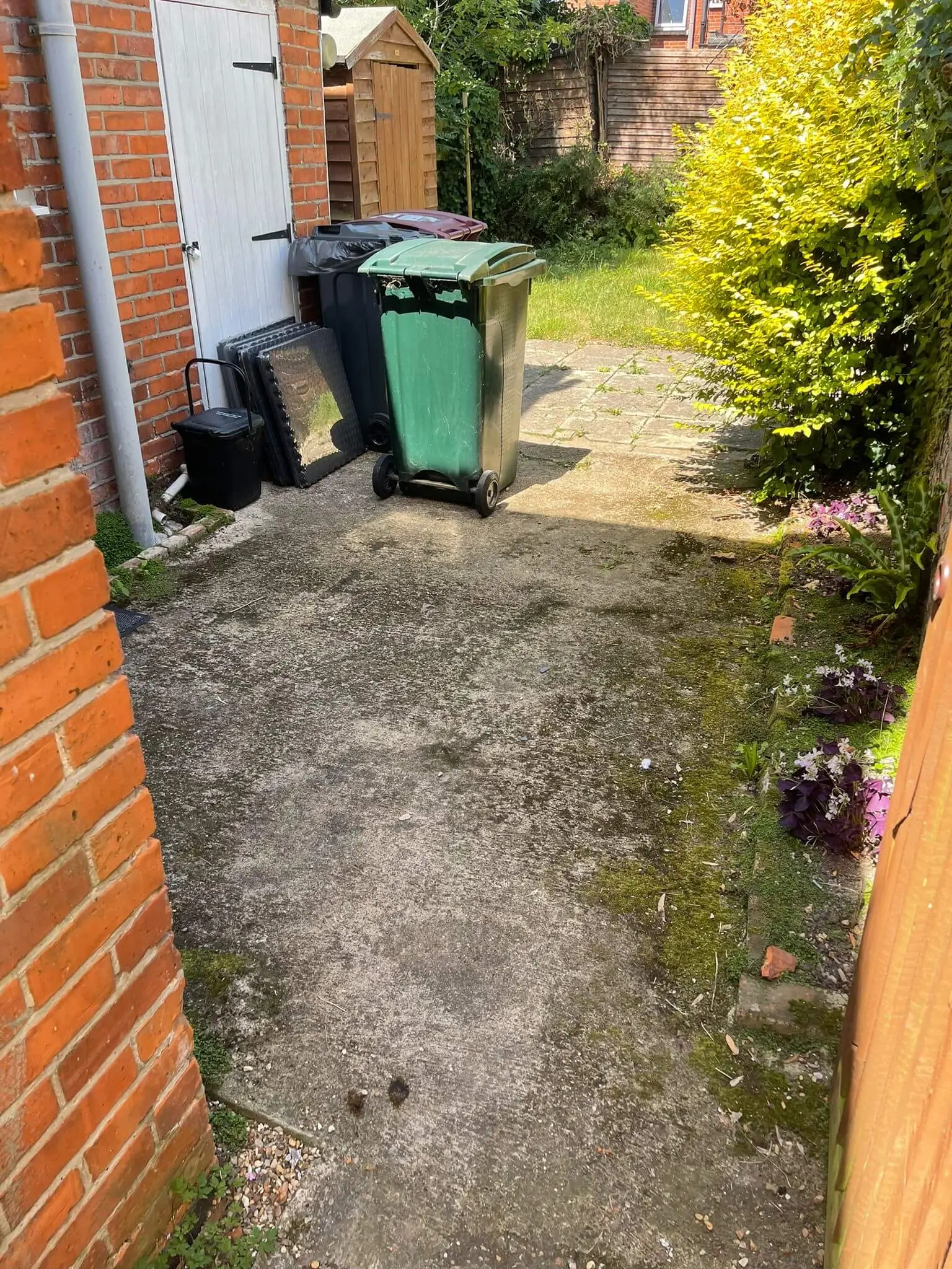 The same driveway and side path cleared, with wheelie bins and a food caddy left against the garage.