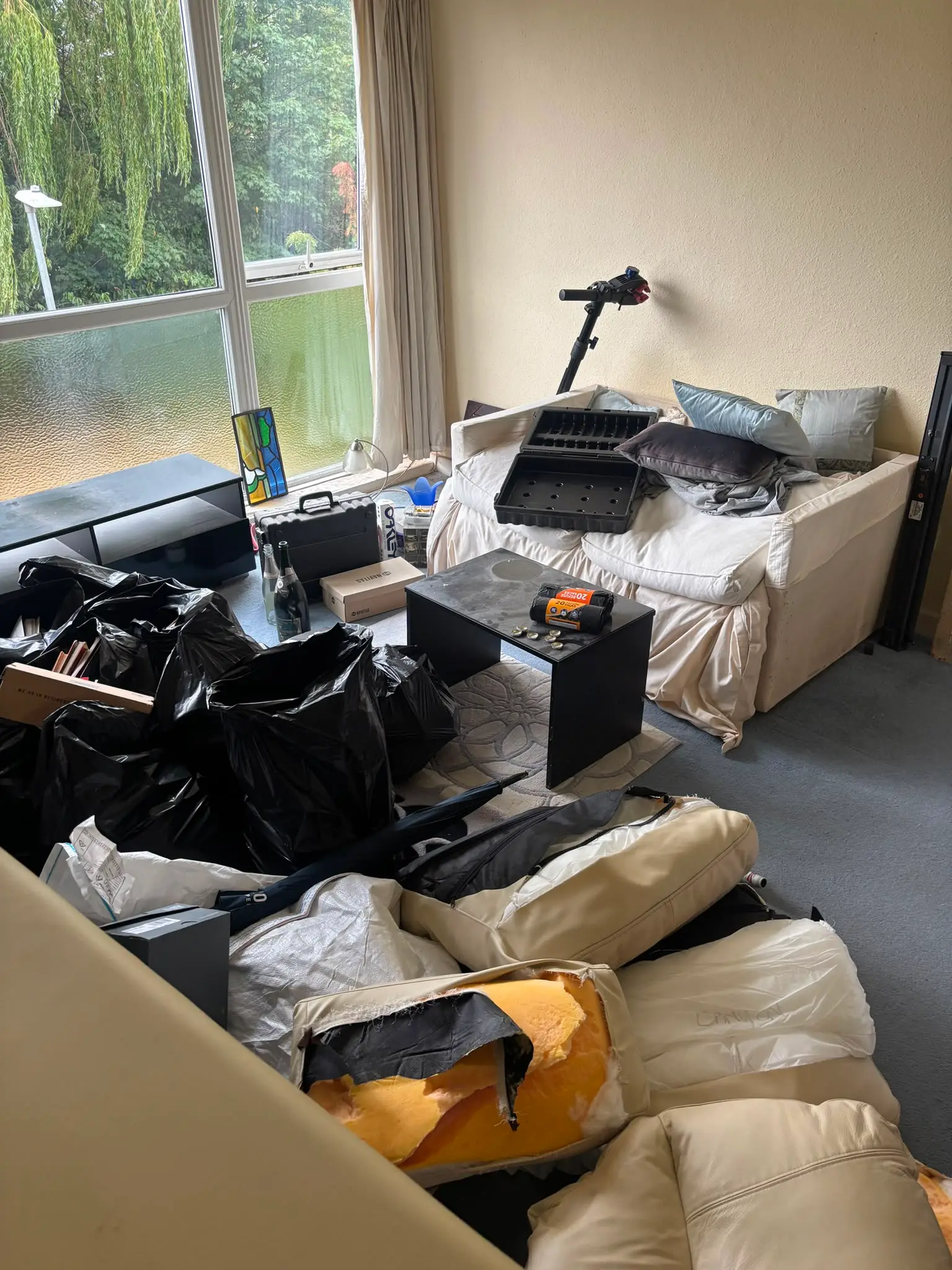 Bagged items, sofa cushions and household clutter inside a flat before it is cleared.