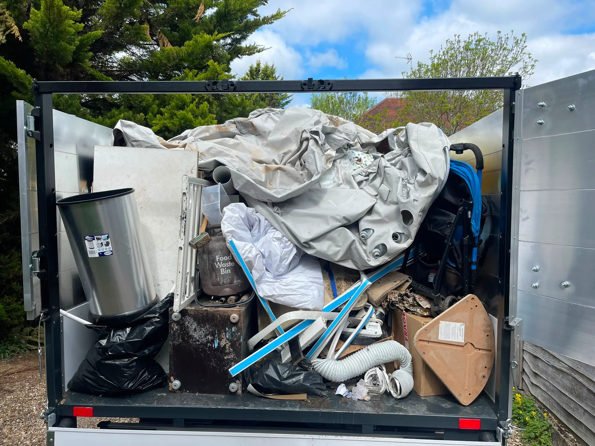 Clearance vehicle fully loaded with bulky household waste ready for removal.
