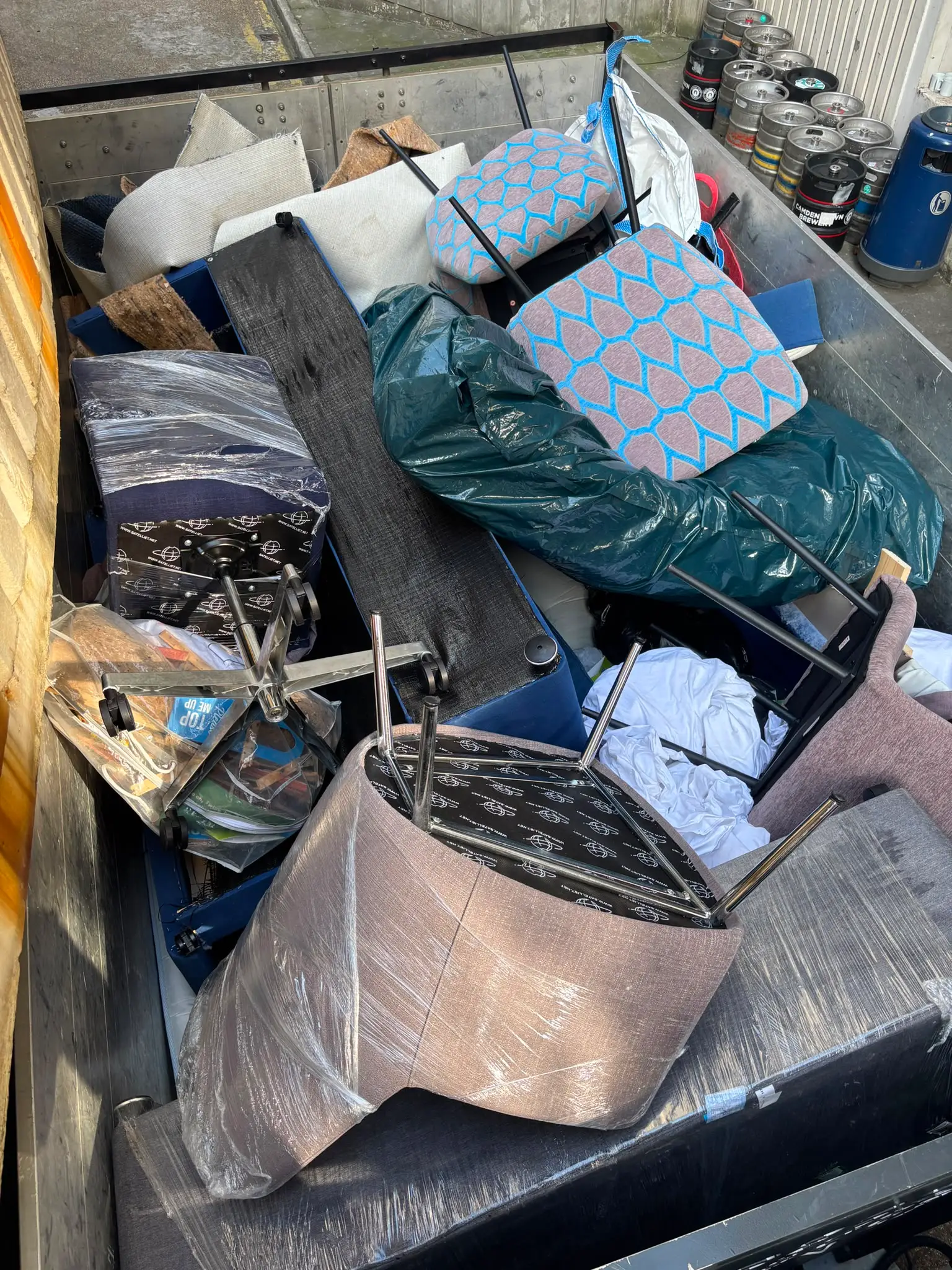 Mixed furniture, mattresses and bagged waste loaded onto the tipper body during a clearance.
